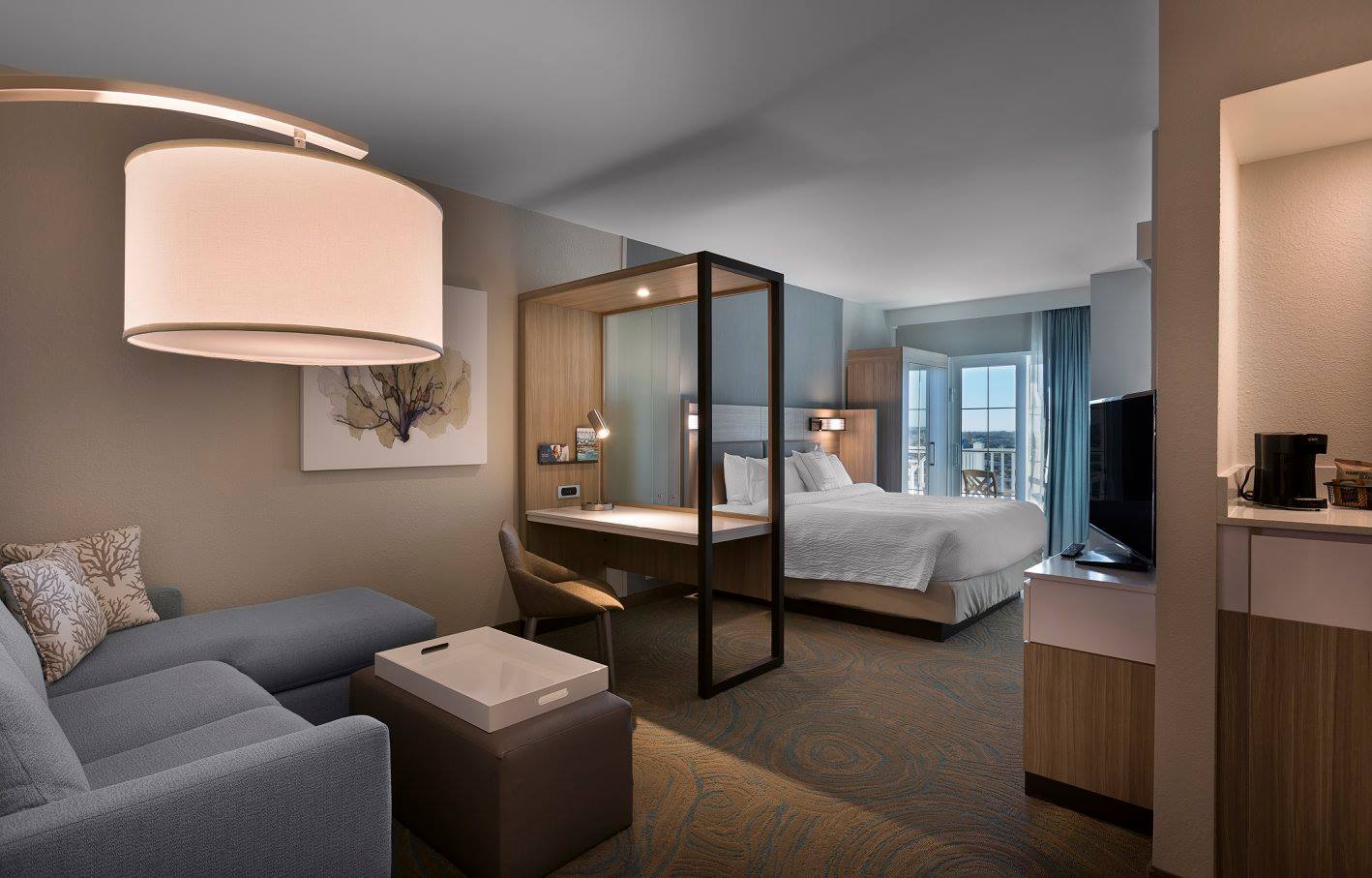 Modern hotel room with bed and sofa.