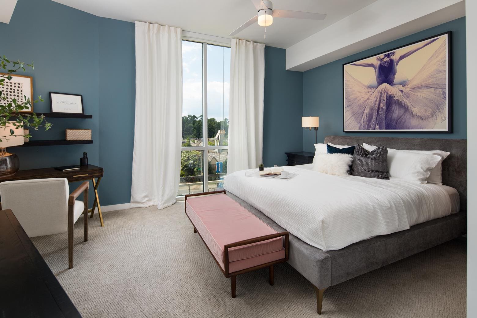 Modern bedroom with blue walls and artwork.