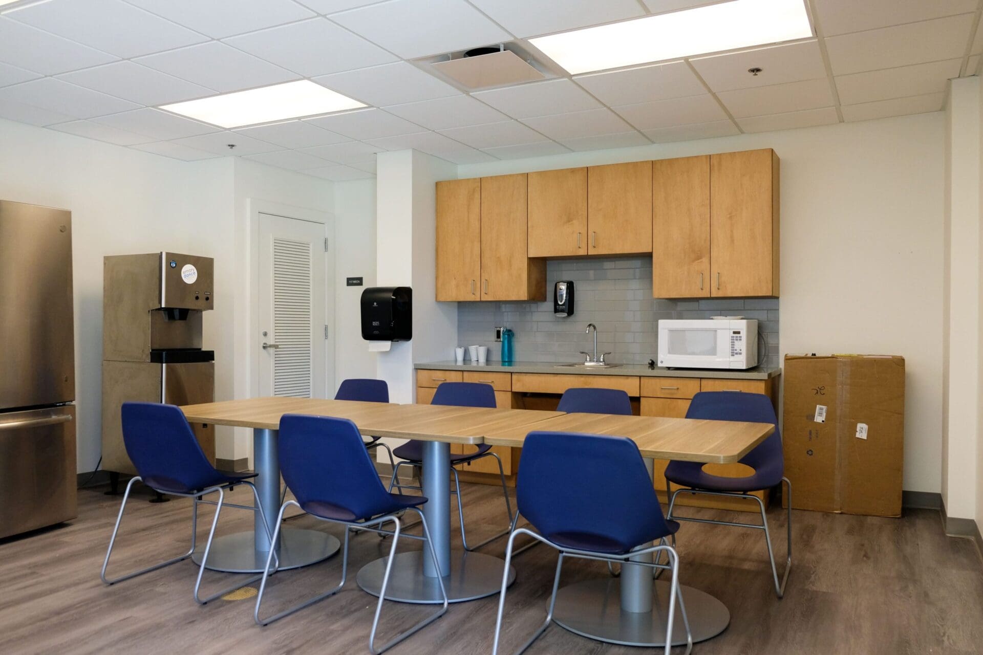 Office kitchen with table and blue chairs.