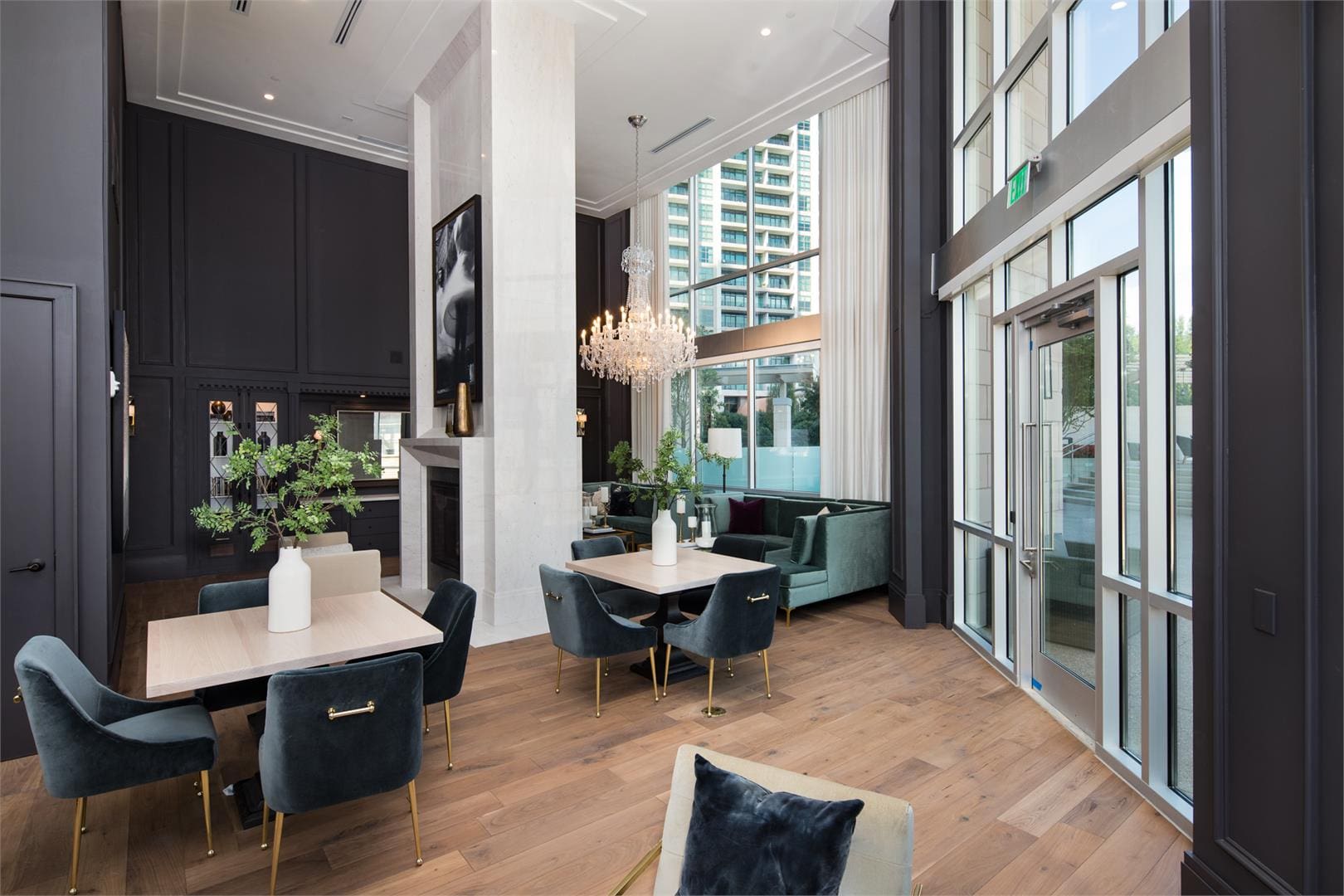 Modern lounge with chandeliers and large windows.