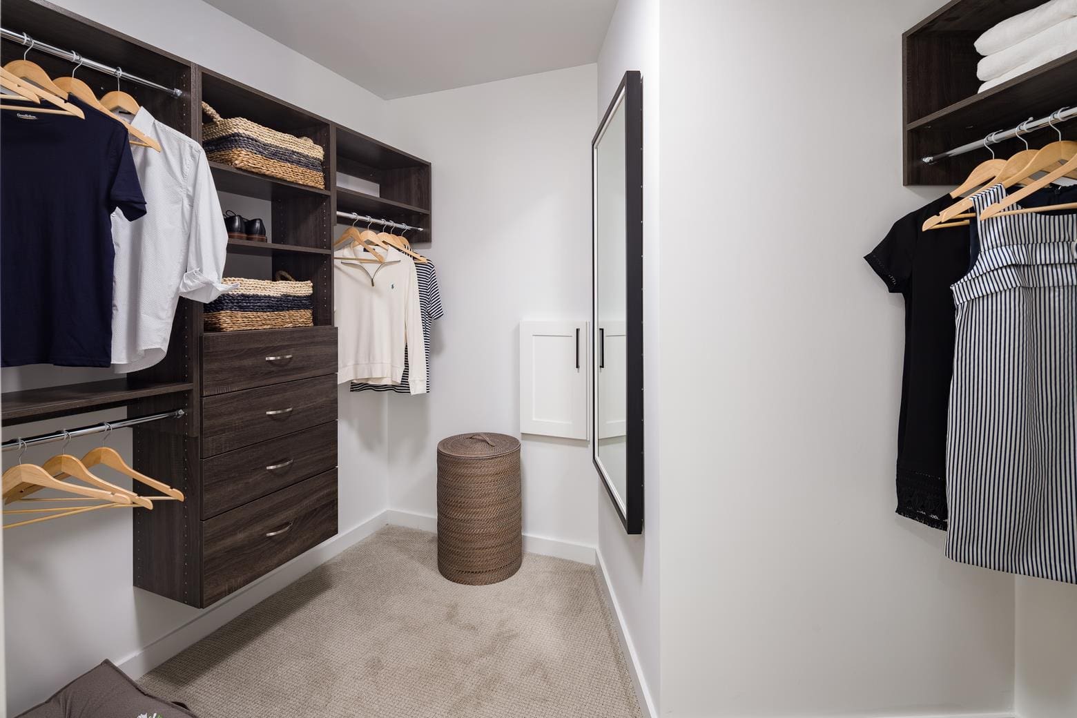 Walk-in closet with clothes and mirror.