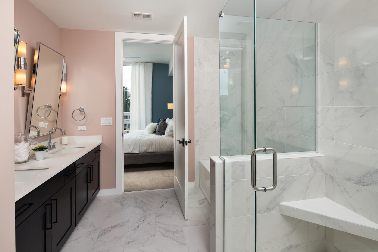 Modern bathroom with glass shower and bedroom.