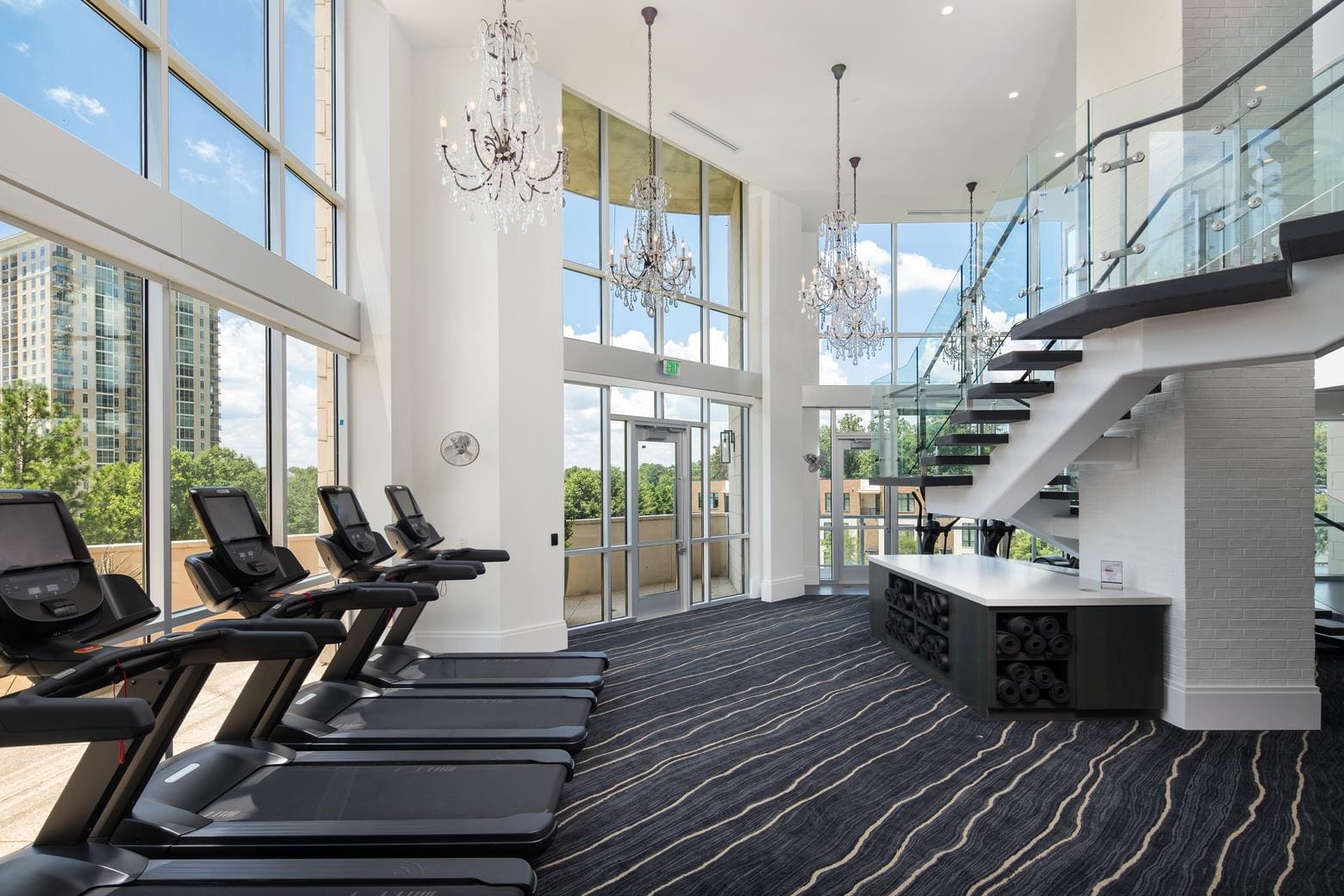 Modern gym interior with treadmills and stairs.
