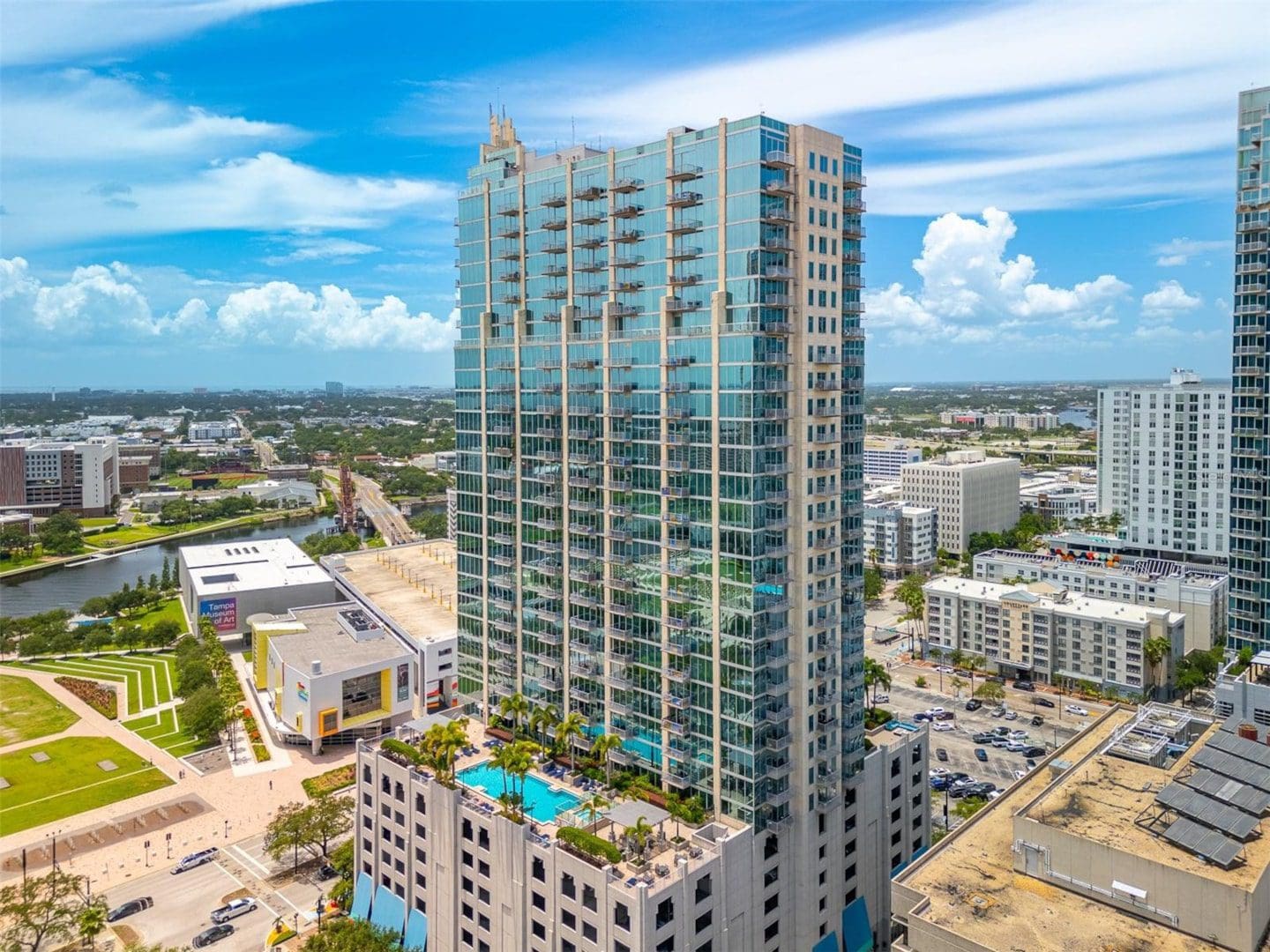 Modern skyscraper with rooftop pool and cityscape.