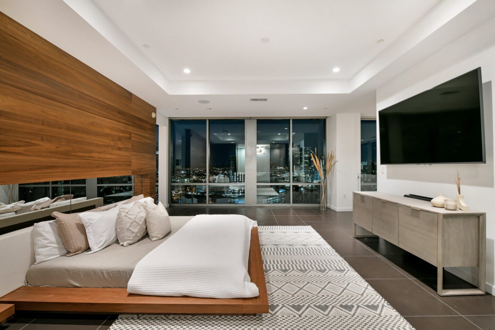Modern bedroom with city view and TV.