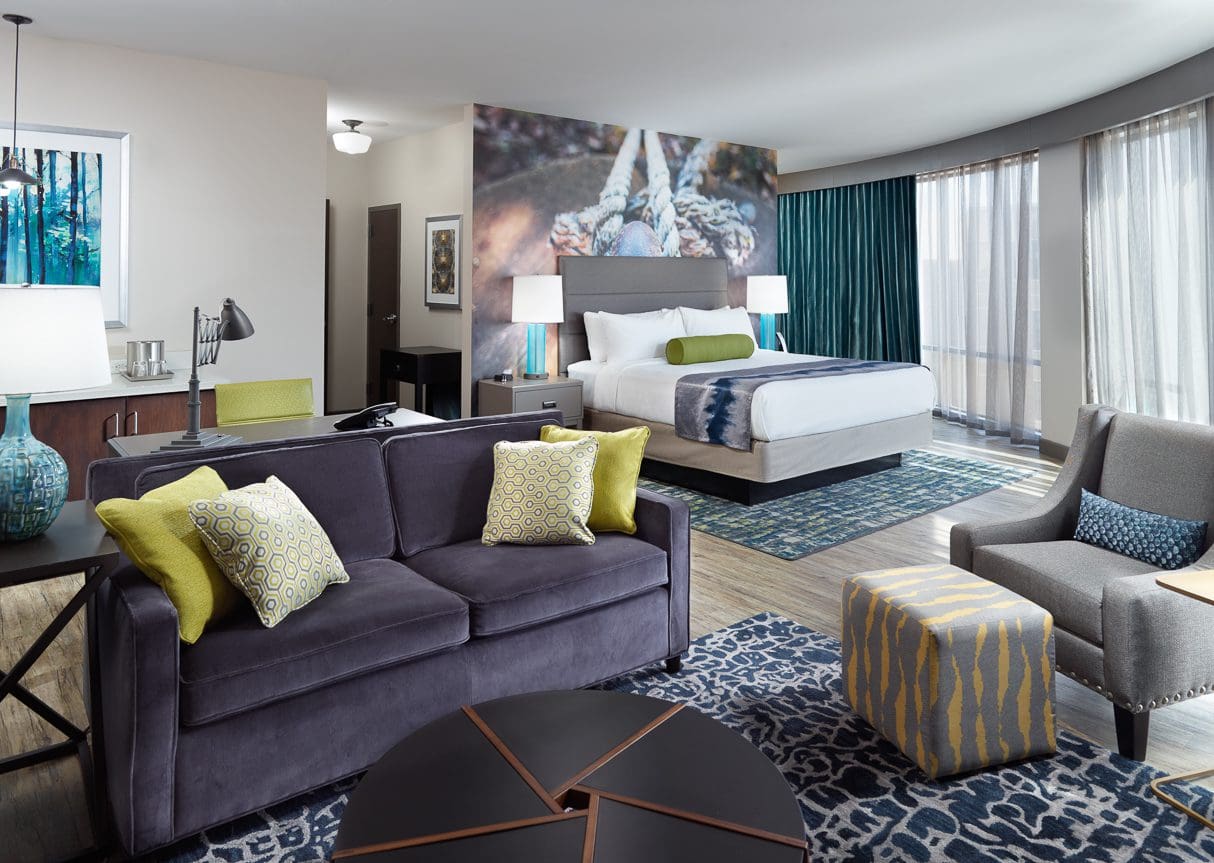 Modern hotel room with bed and seating area.