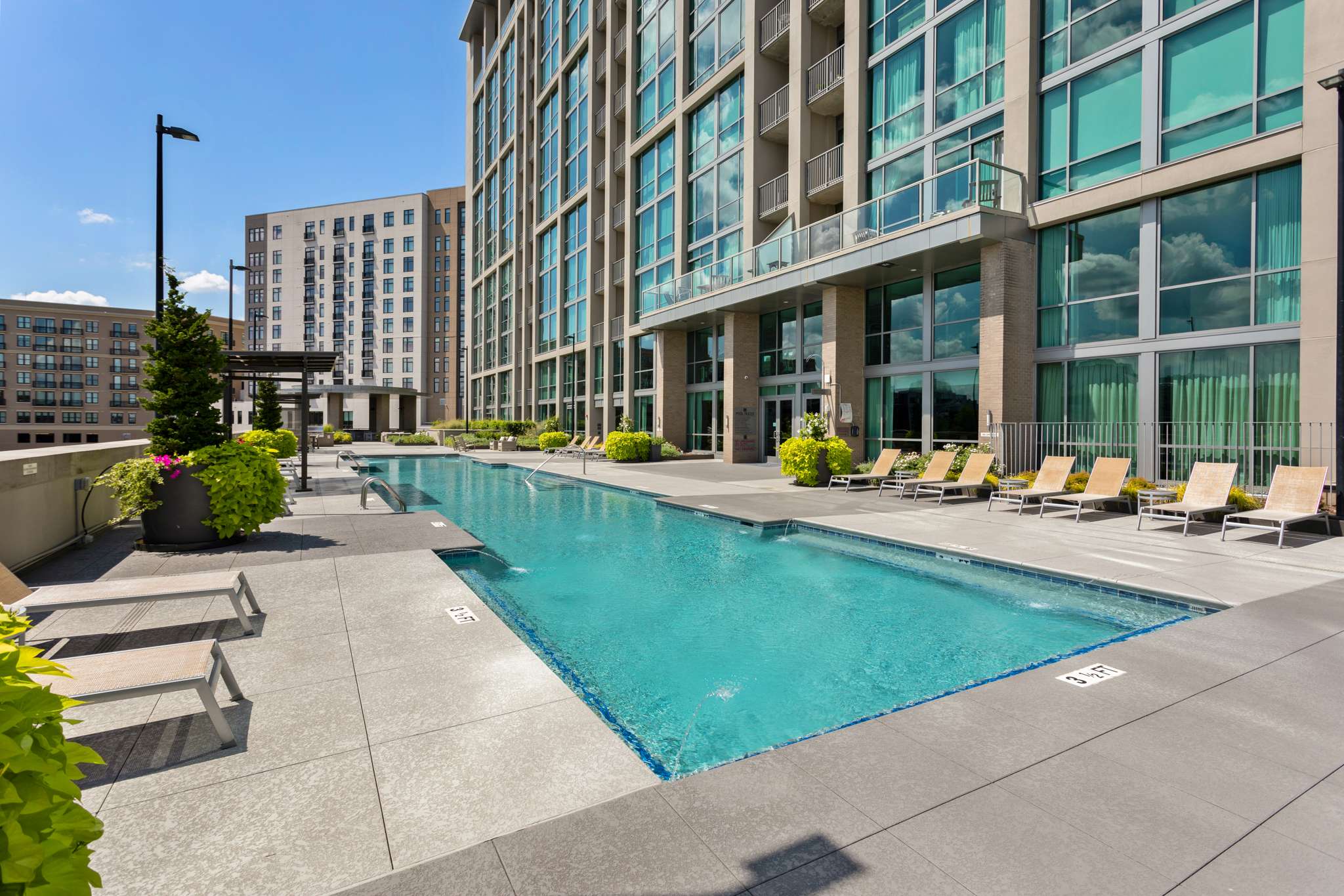 Outdoor pool beside modern high-rise building.