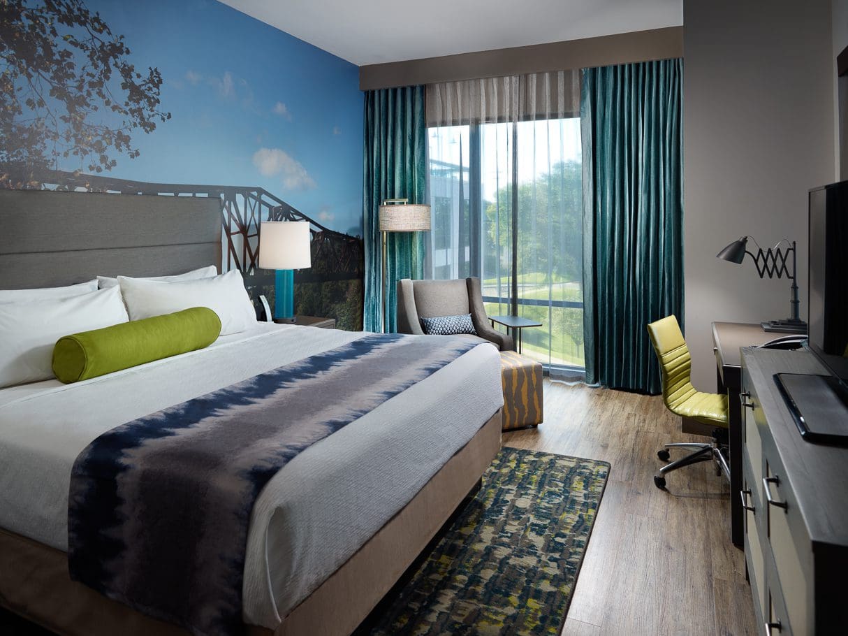 Modern hotel room with large bed and window.