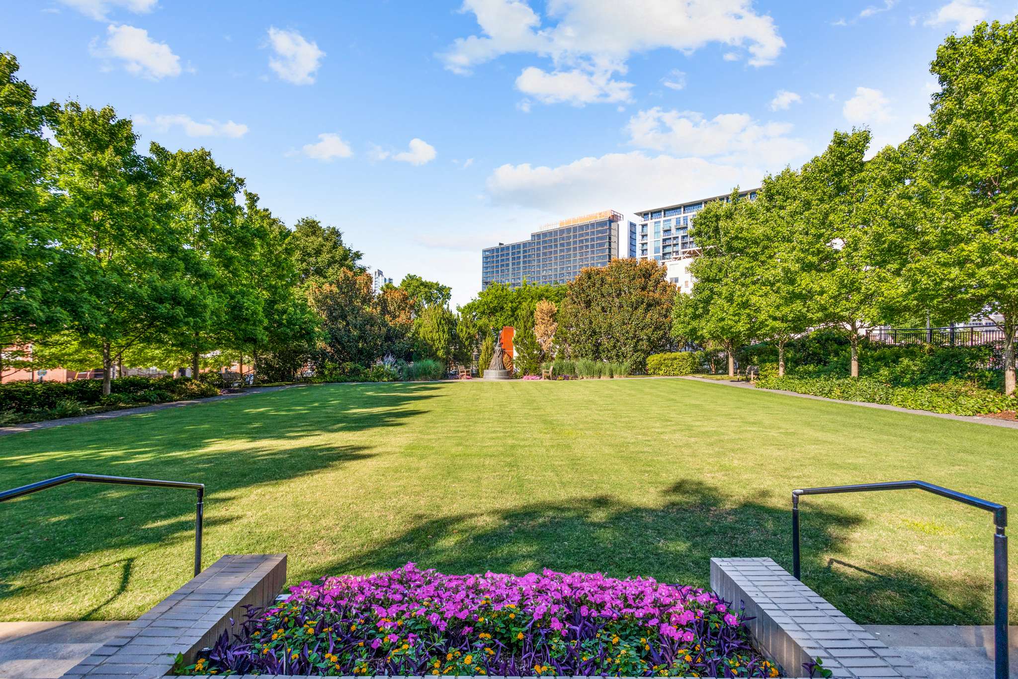 Park with lawn, trees, and colorful flowers.