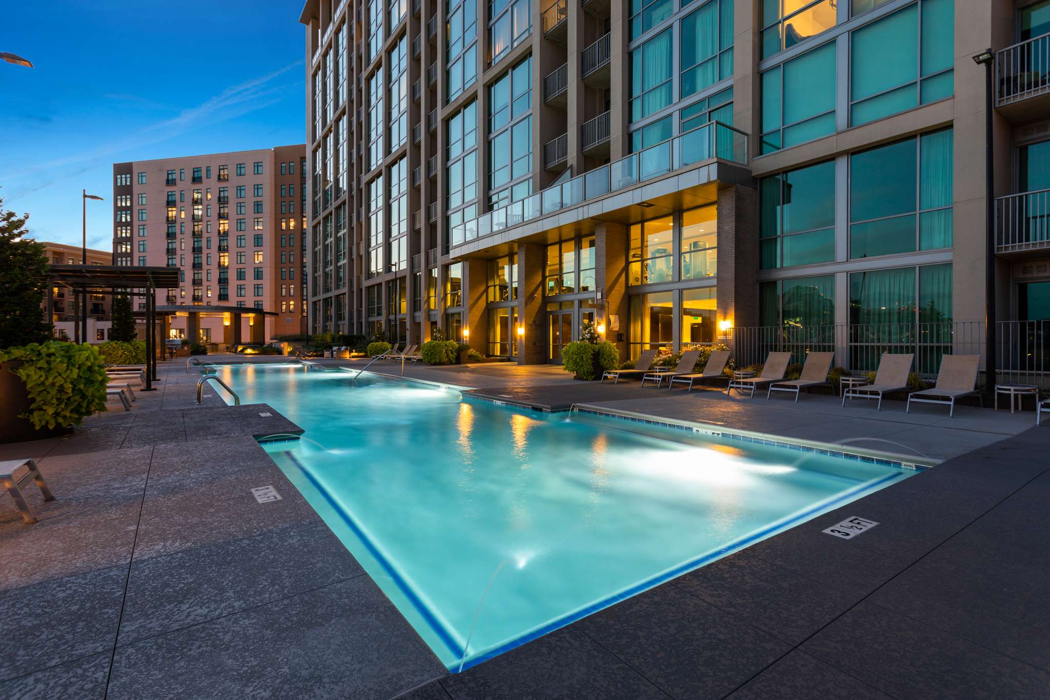 Outdoor pool beside modern glass building.