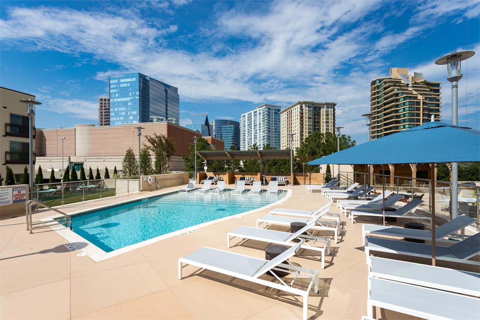 Rooftop pool with lounge chairs and cityscape.