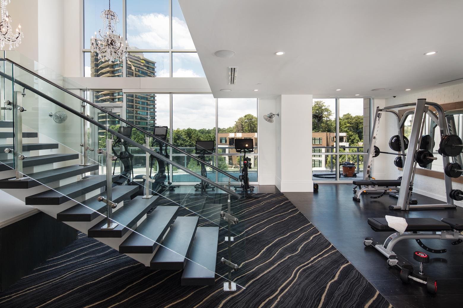 Modern gym with staircase and large windows.