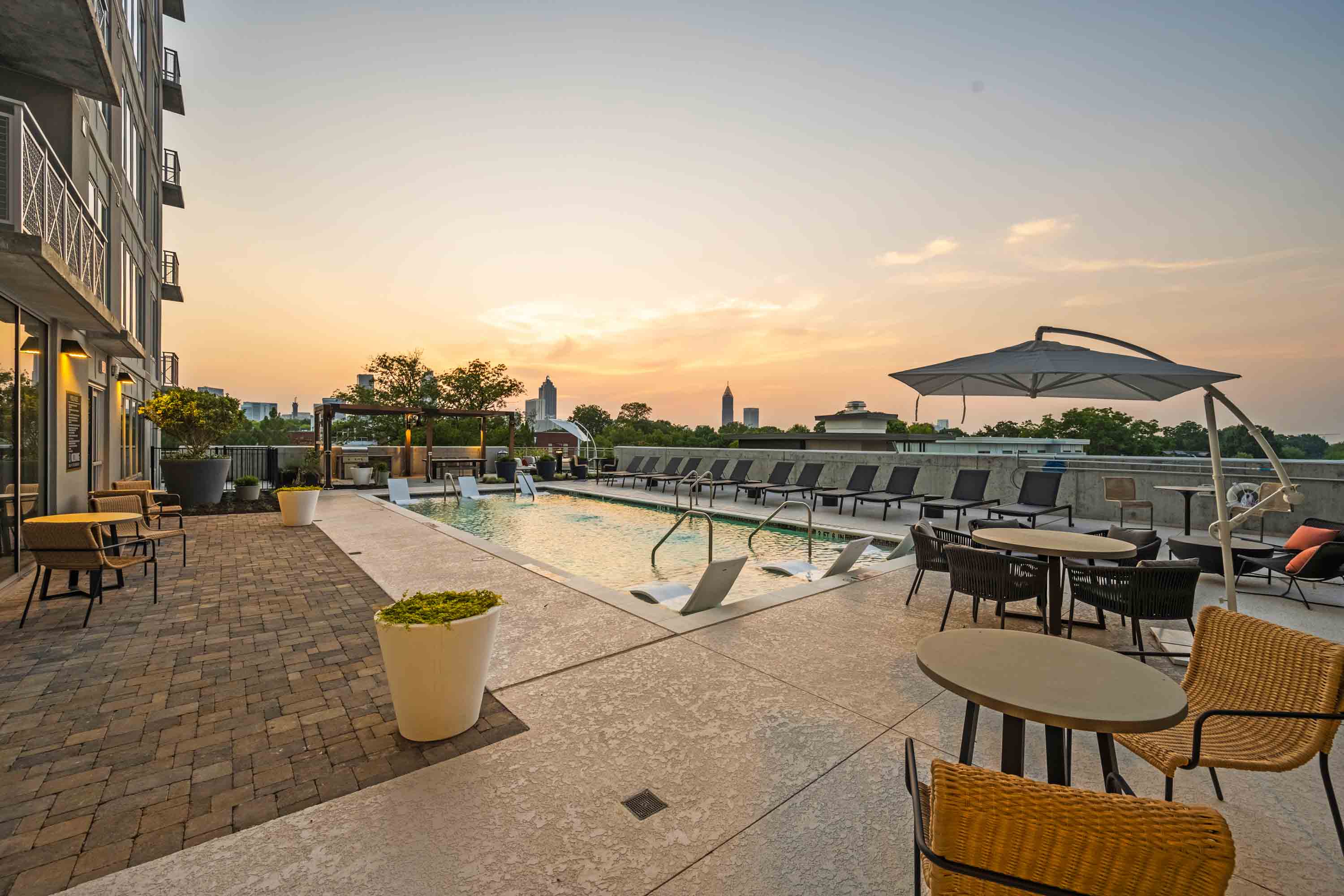 Rooftop pool with city skyline at sunset.