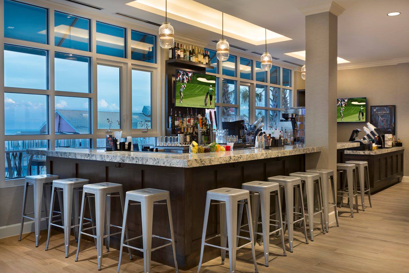 Modern bar with stools and large windows.