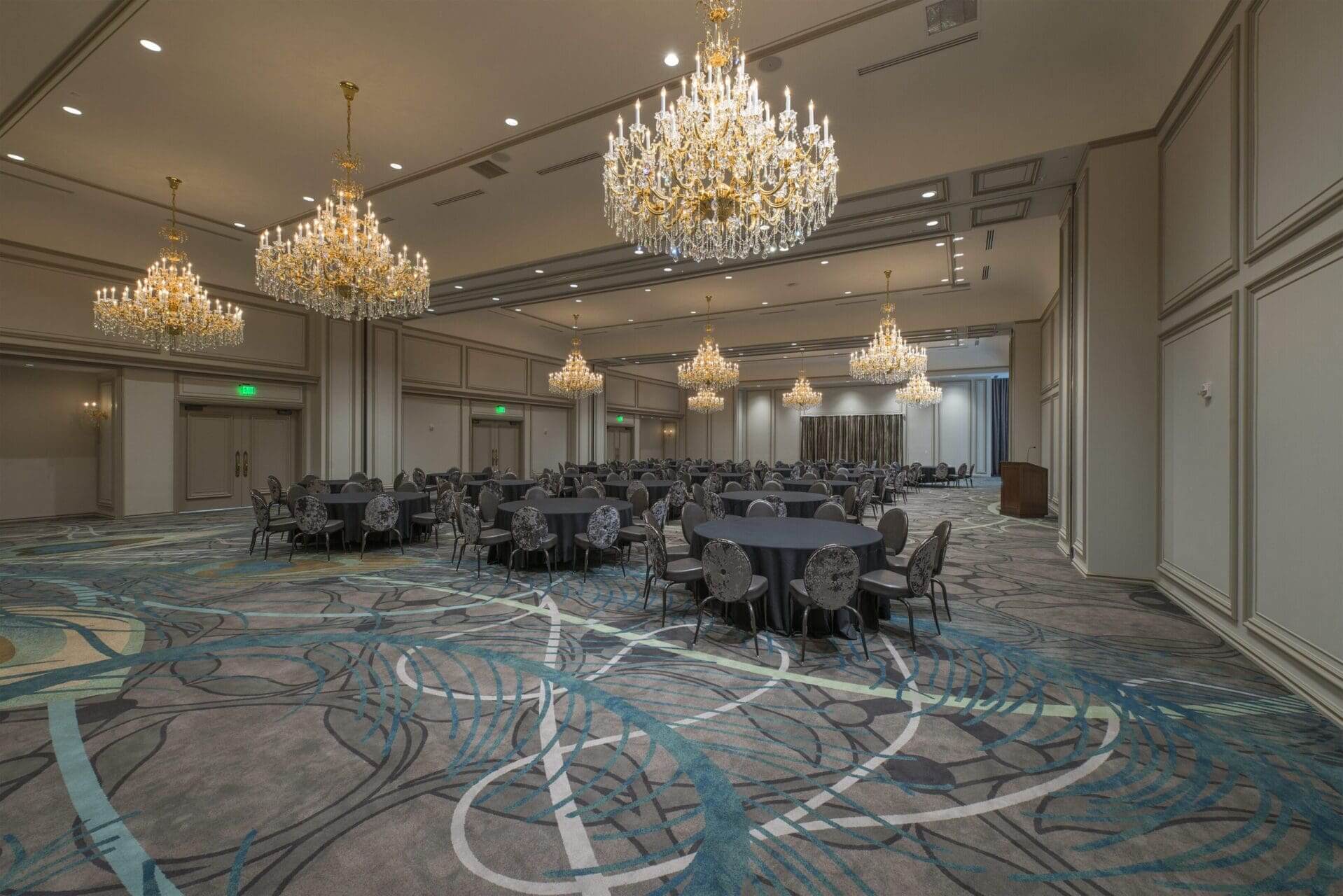 Elegant ballroom with chandeliers and round tables.