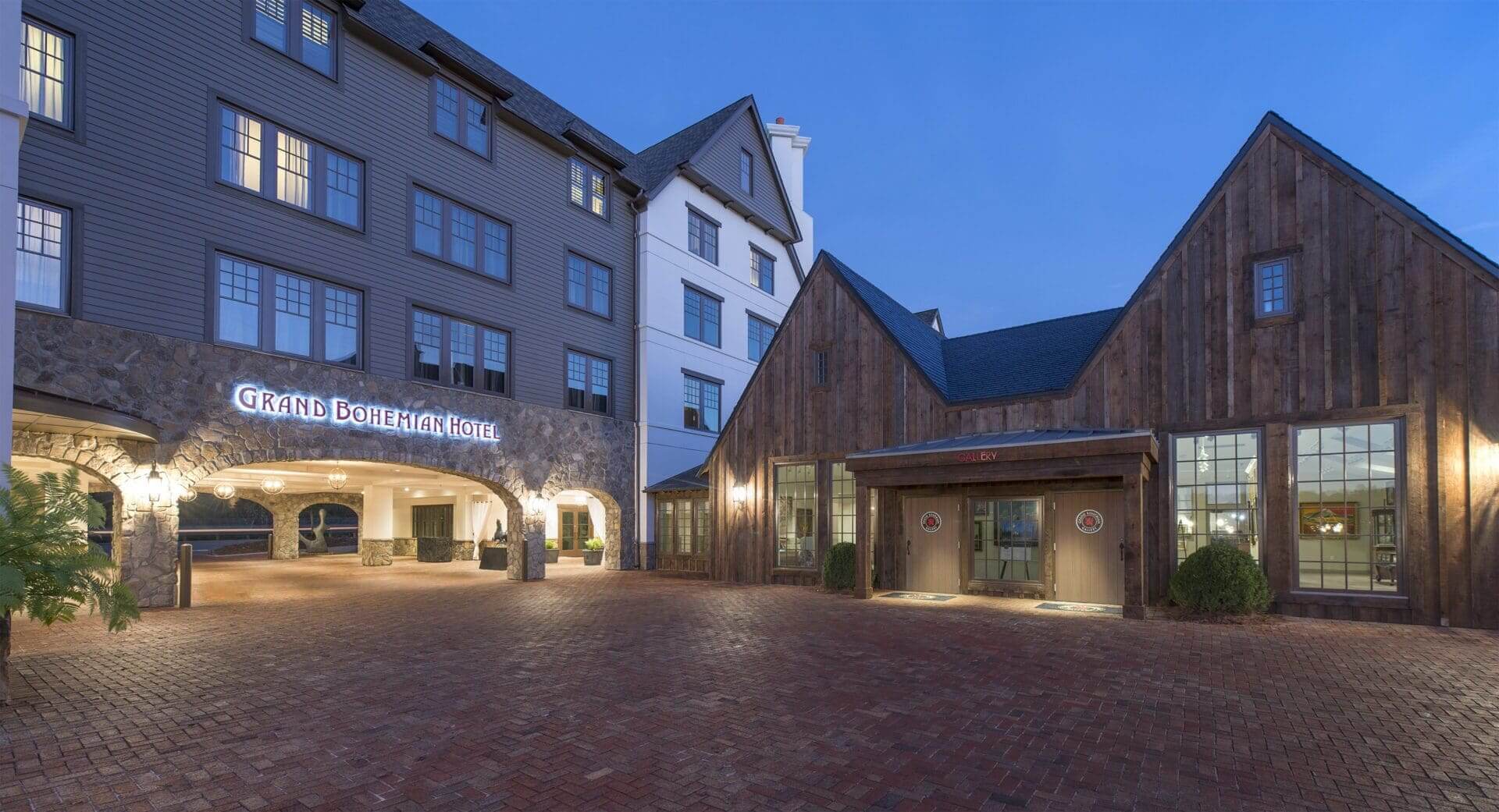Hotel entrance with illuminated sign at dusk.