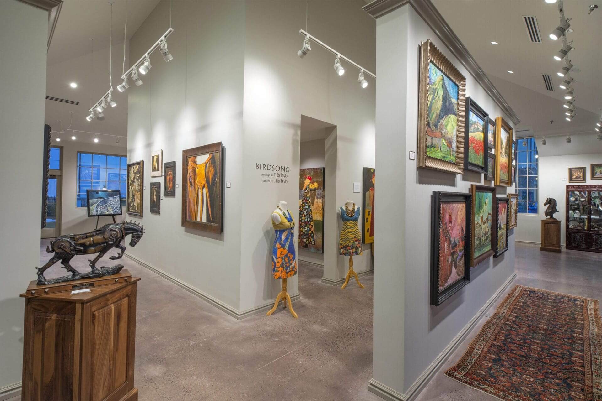 Art gallery interior with various paintings displayed.