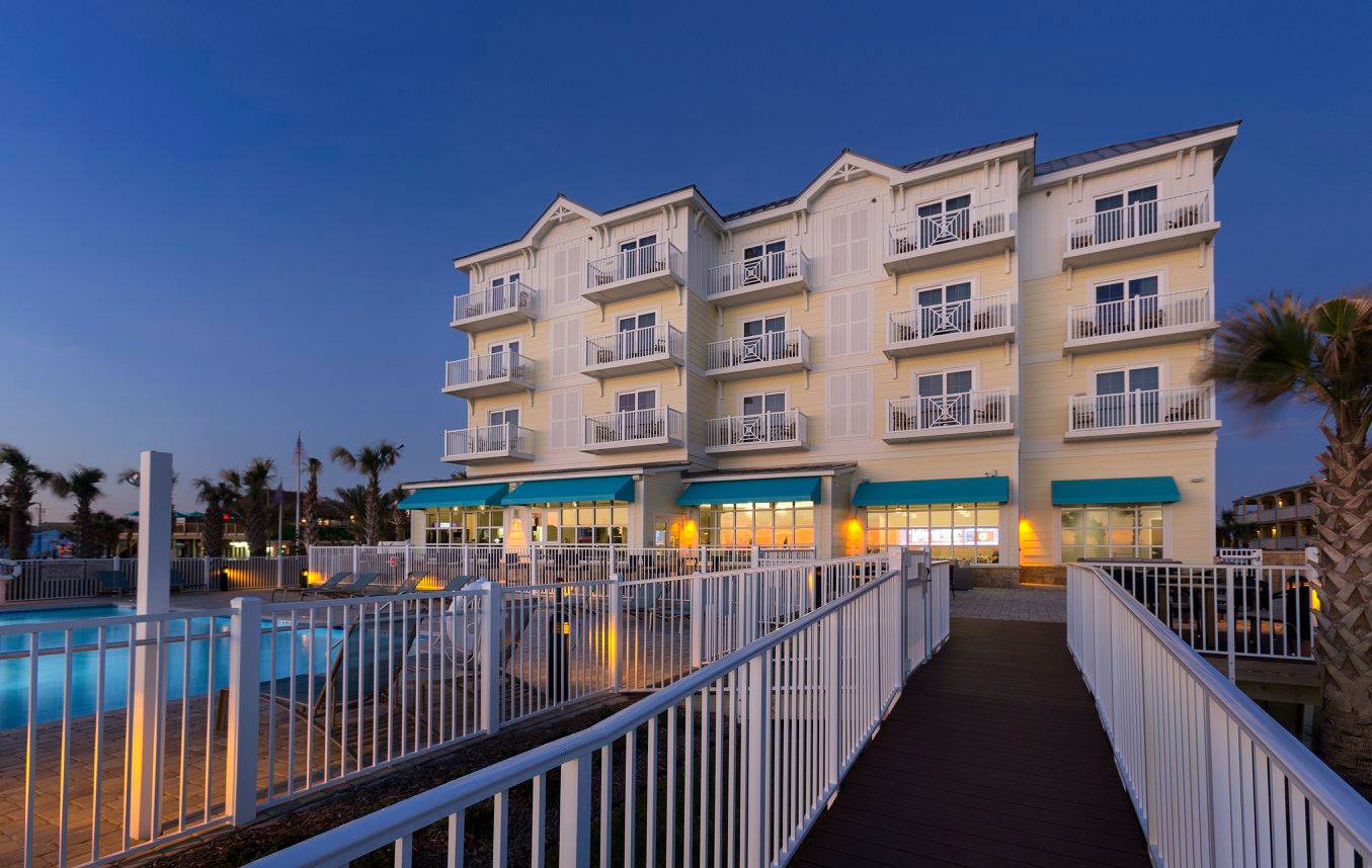 Hotel exterior with pool at dusk.