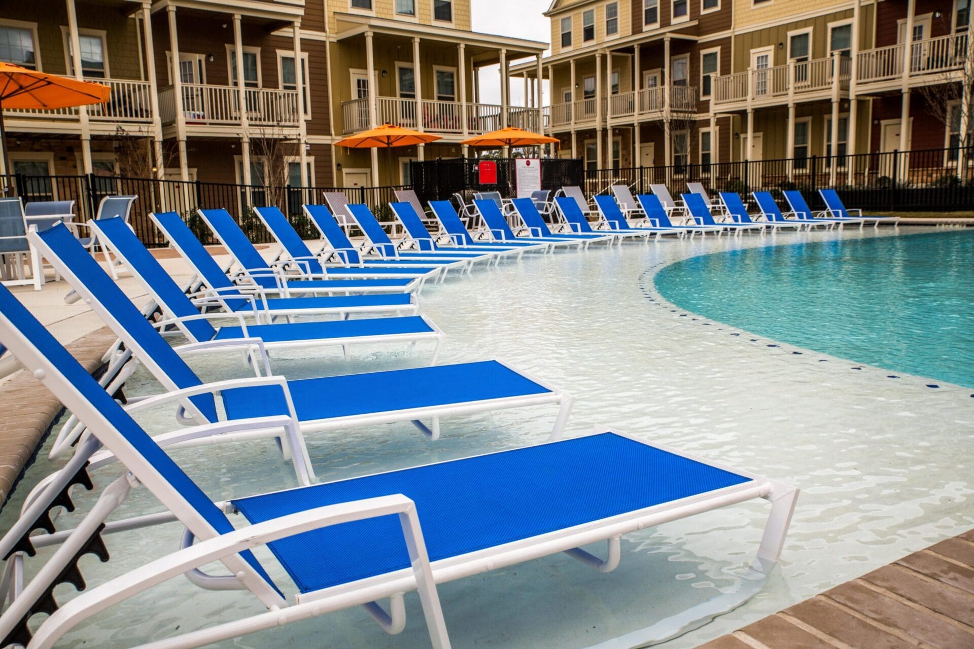 Blue loungers by a curved swimming pool.