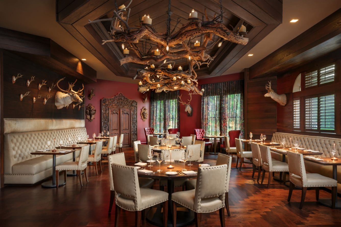 Rustic restaurant interior with antler chandeliers.
