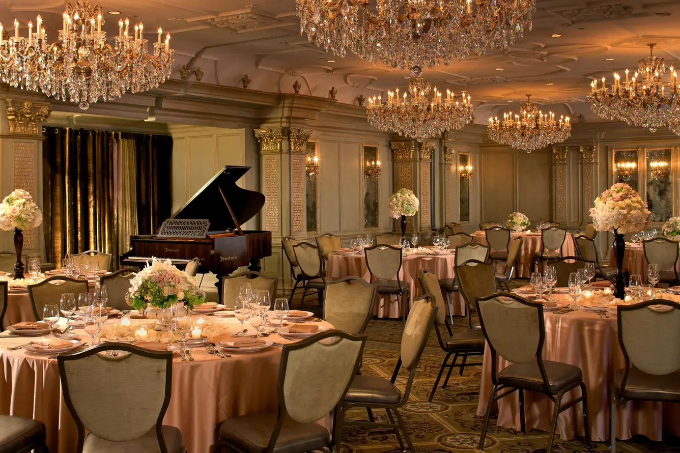 Elegant banquet hall with chandeliers and piano.