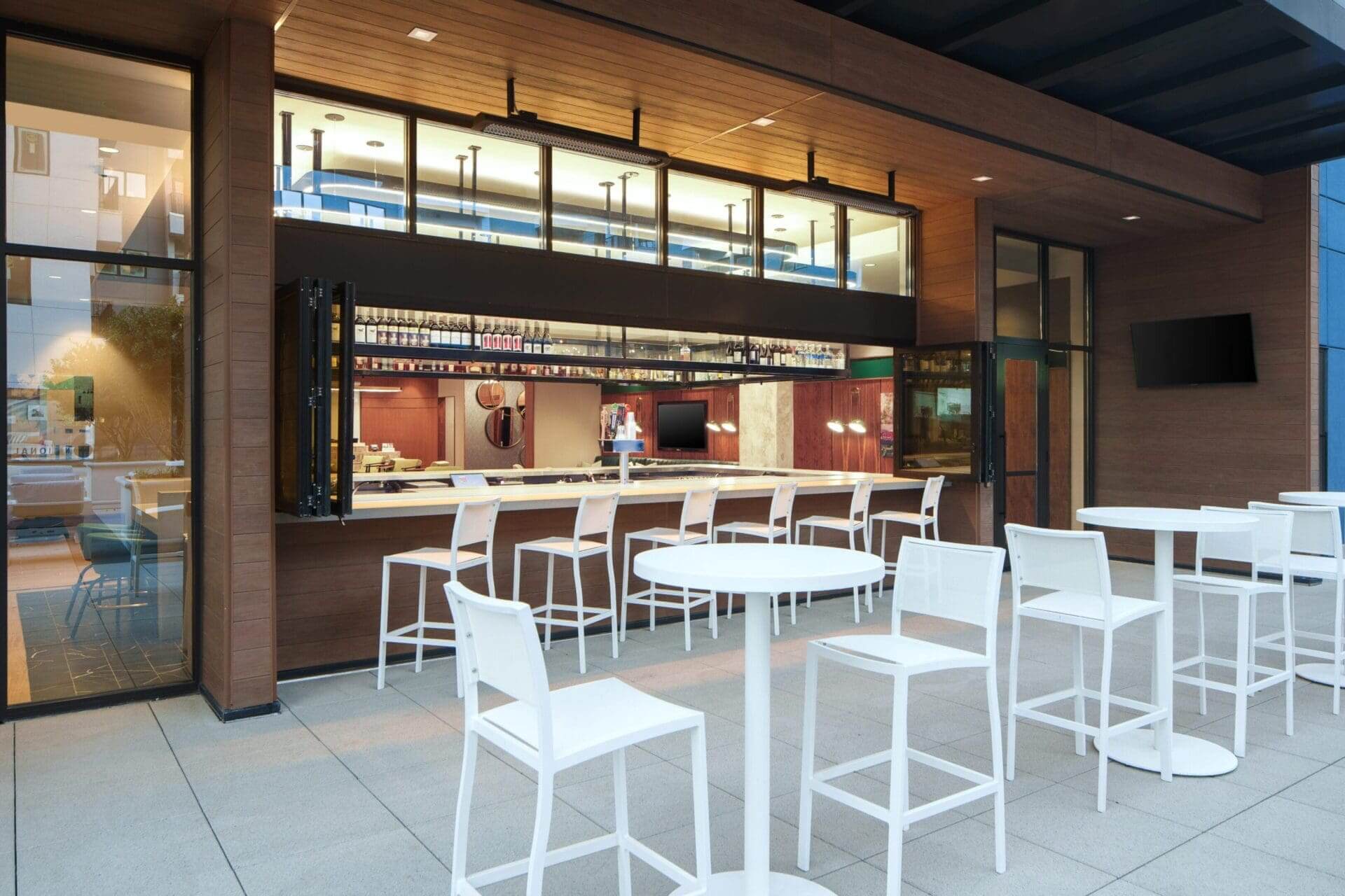 Outdoor bar with white tables and chairs.