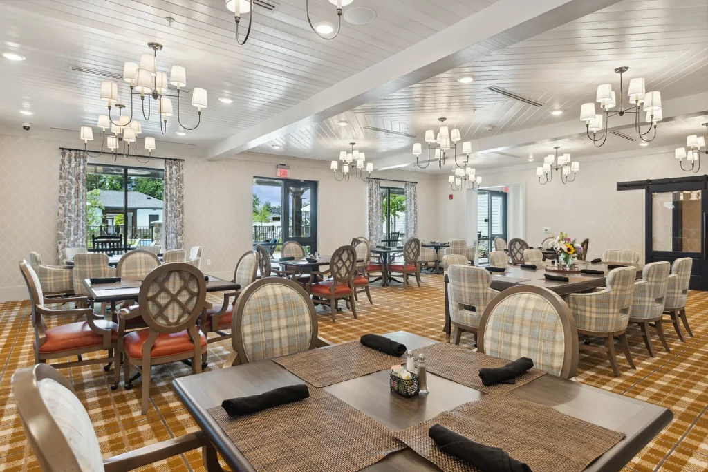 Bright dining area with round tables and cushioned chairs on wooden flooring.