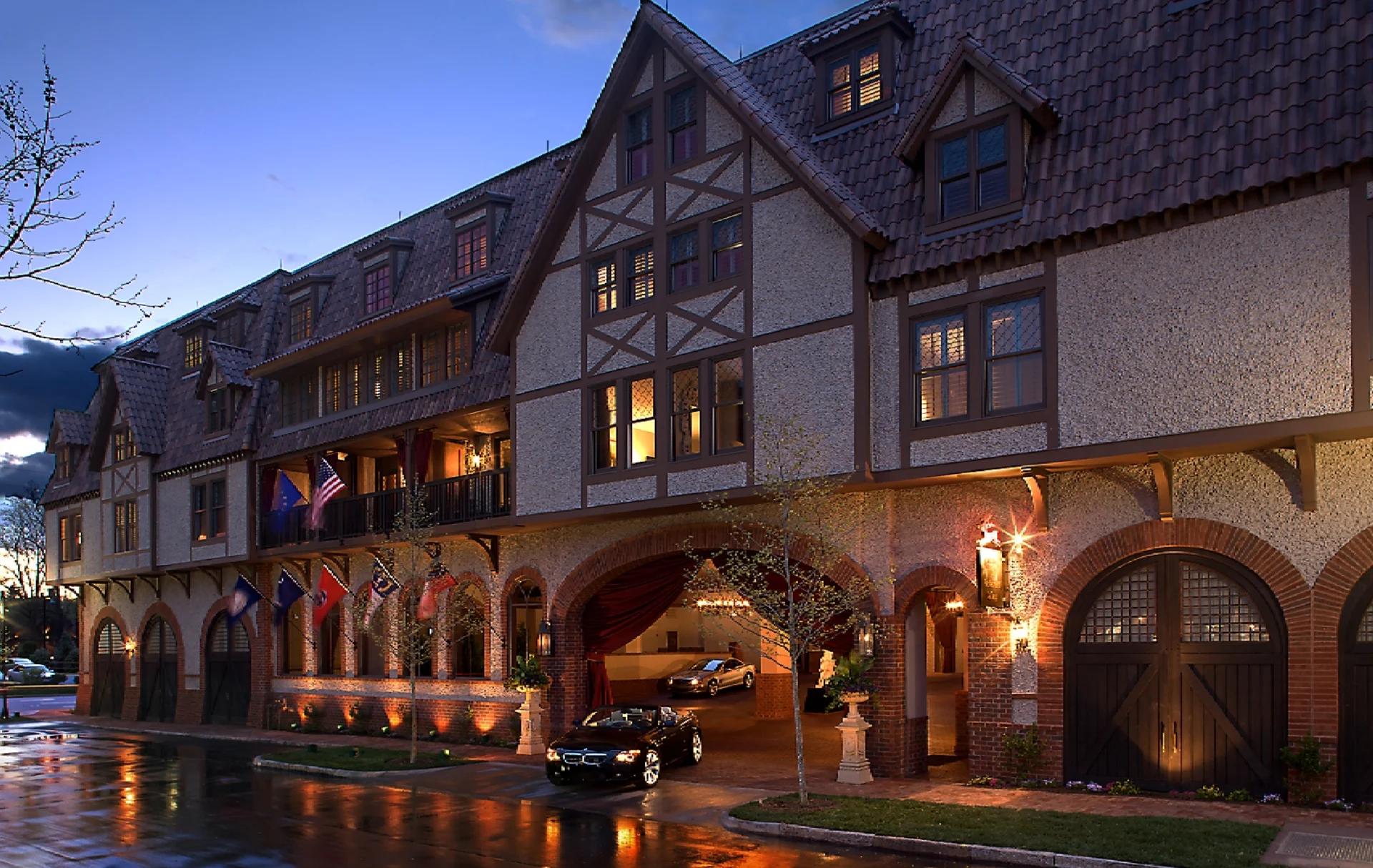 Historic hotel entrance illuminated at dusk with parked cars.